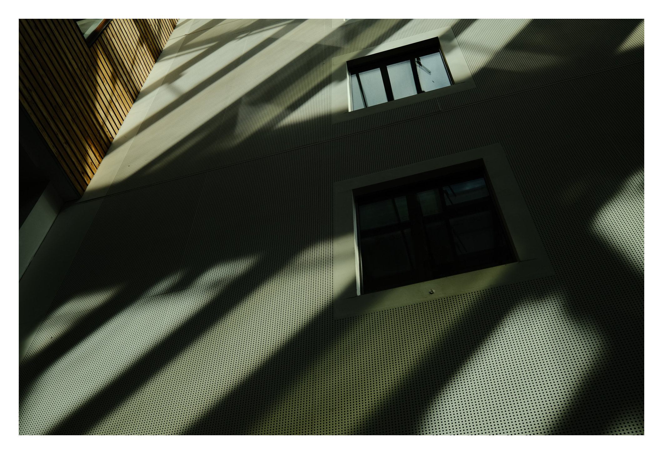 Grünliche Fassade mit diagonalem Schattenspiel