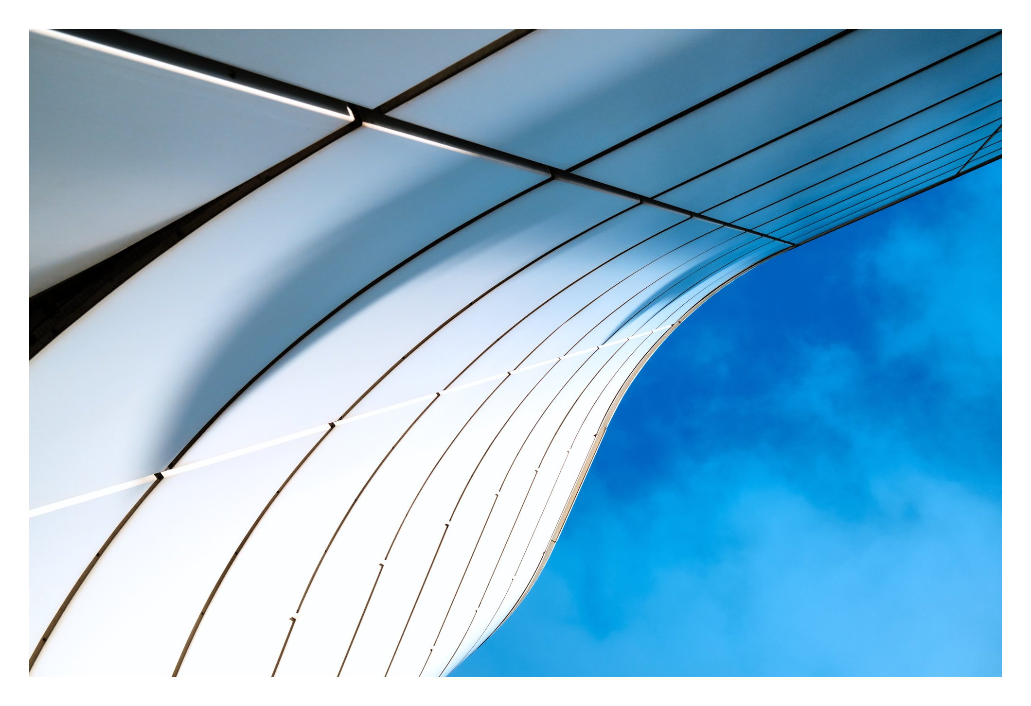 Helle geschwungene Architektur vor einem blauen Himmel