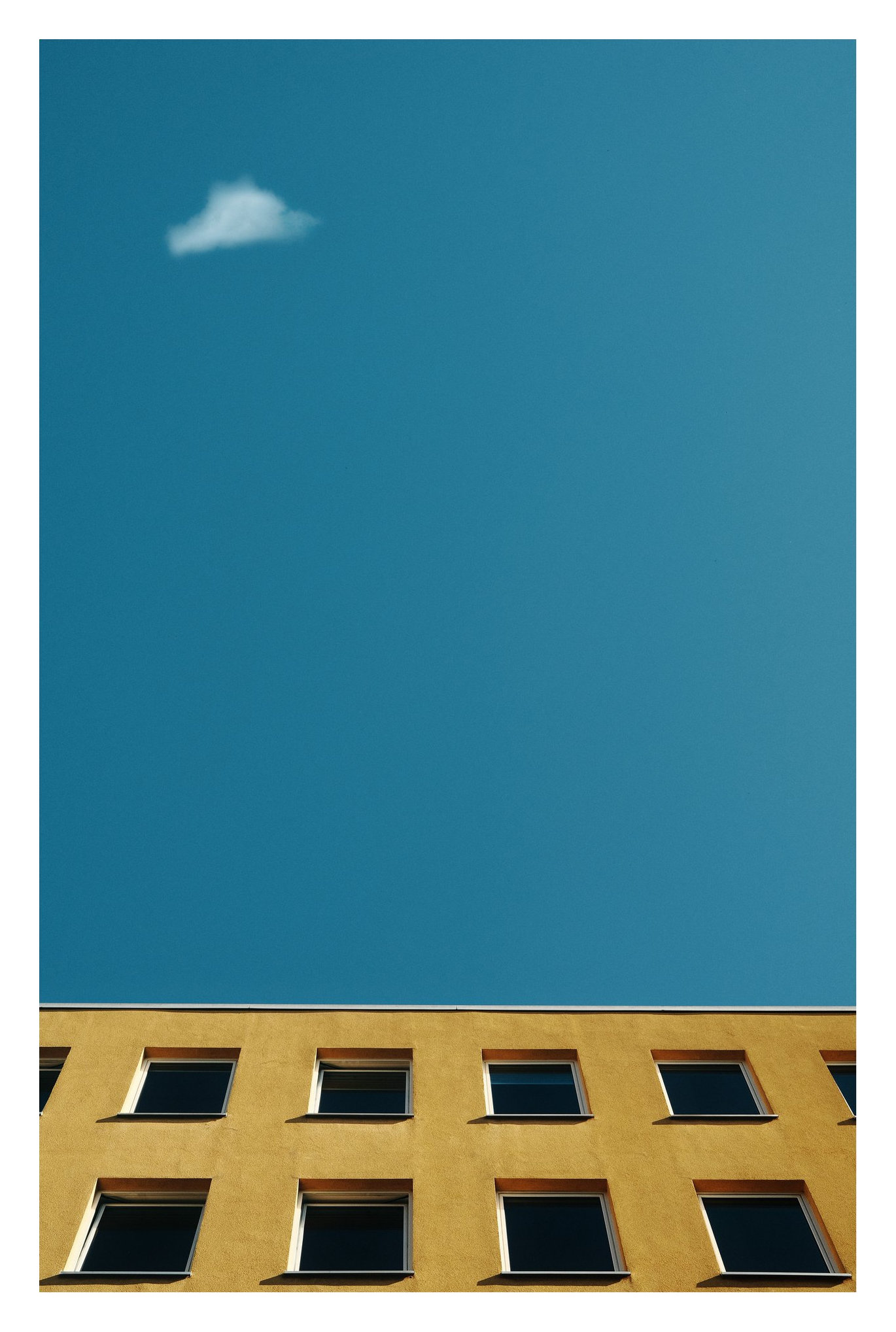 Kleine Wolke über einer Hausfassade vor blauem Himmel